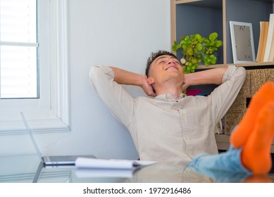 Satisfied teenager happy to finish work with laptop at home, raises hands and puts feet up on table, relaxing after hard working day in expectation of weekend leave, relaxed workday, no stress