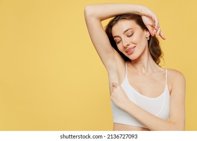 Satisfied tender caucasian young brunette woman 20s in white brassiere underwear raise up hand show soft perfect shaved armpit isolated on plain yellow background studio Female beauty bodycare concept