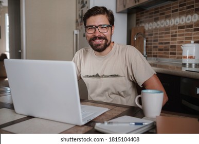 Satisfied with work done. Happy young man working on laptop while sitting at his working place in home office. Happy employee feeling no stress, relaxing, watching funny video after successful working