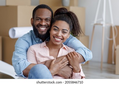 Satisfied young african american wife and husband hugging in new apartment with boxes. Happy couple enjoying purchase of new flat and result of renovation in own home. Moving and relocation at house - Shutterstock ID 2055846710