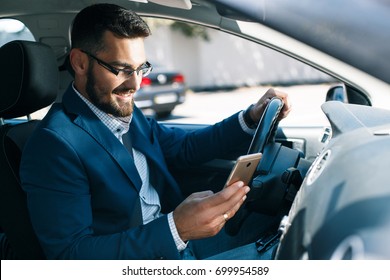 Satisfied Young Business Man With Phone In Car