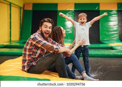 Satisfied young family with their little son spending time on a trampoline together at the entertainment centre - Powered by Shutterstock