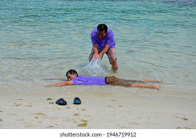 Satun, Thailand, March 23, 2013  Asian Man Bail Water Out His Friend On The Beach In The South Of Thailand