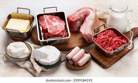 Saturated fats on tables. Raw meat, sausages, cheese, butter. Bad food concept. 
