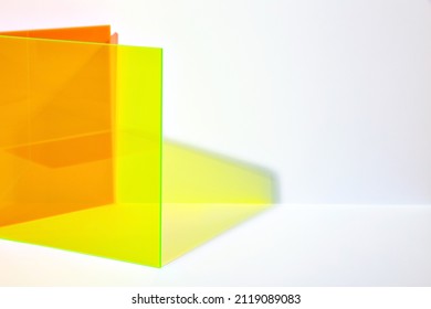 Saturated orange and neon yellow acrylic sheet with long shadow on a bright lit white background. Stylish abstract background. Stage for advertising, promoting new products.