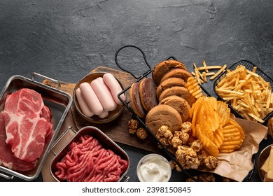 Saturated and trans. Unhealthy food. Sausage, potato, meat, cheese, popcorn, cookies, cream on dark background. Top view, copy space.