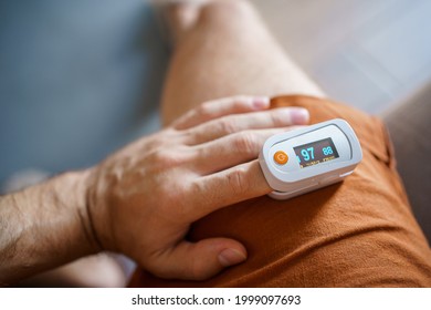 Saturation Device Pulse Oximeter. Self-measurement Of Blood Oxygen Saturation At Home. The Device On The Finger Of A Man's Hand With A Reading Of 98.