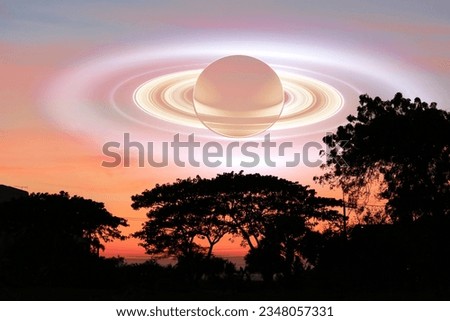 Saturn shadow upper ring near earth over  silhouette top tree and the orange sky sunset cloud, Elements of this image furnished by NASA