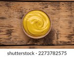 Sauce bowl with delicious mustard and seeds on wooden table, top view