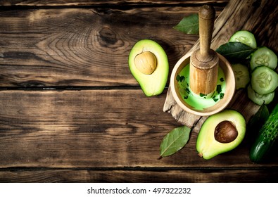 Sauce In A Mortar With Pestle, Avocado And Cucumber. On Wooden Background.