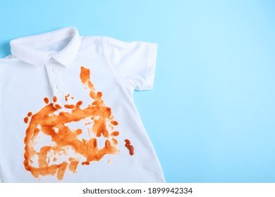 Sauce Spilled On A White Shirt. The Concept Of Cleaning Stains On Clothes. Means Of Cleaning Stains. Isolated On A Blue Background. High Quality Photo