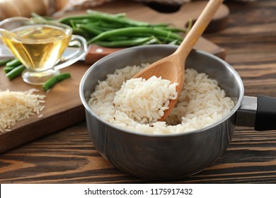 Saucepan With Boiled Rice On Wooden Table