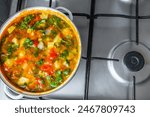 a saucepan full of traditional  Romanian vegetable soup on a gas stove