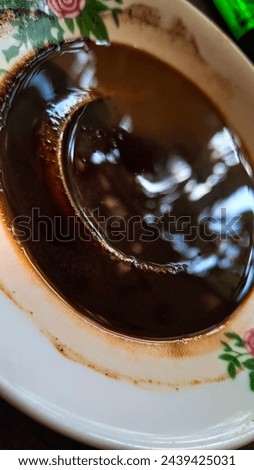 a saucer containing traces of the dregs of black coffee which is still strong