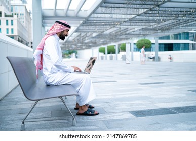 Saudi Arab business man on laptop working outdoor wearing traditional dress. Muslim businessman from Saudi Arabia typing