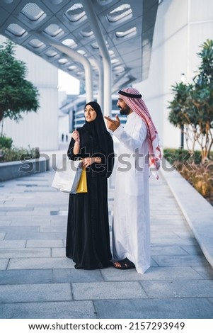 Saudi Arab family shopping outdoor. Muslim couple happy enjoying shop day wearing traditional dress
