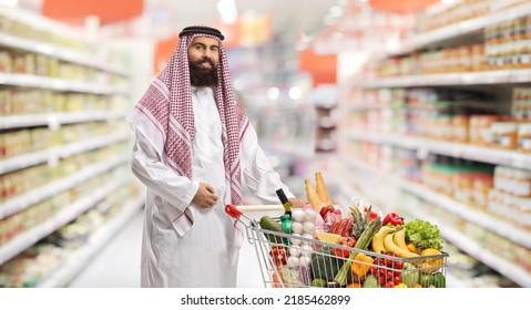 Saudi Arab Man With A Shopping Cart Full Of Food Products Inside A Supermarket