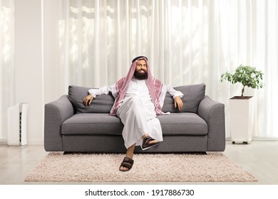 Saudi Arab Man Sitting On A Gray Sofa At Home And Looking At Camera