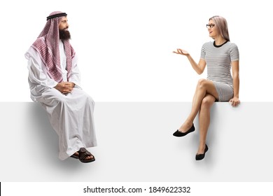 Saudi Arab Man In A Traditional Thobe Talkign To A Young Blond Woman And Sitting On A Panel Solated On White Background