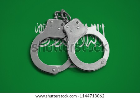 Saudi Arabia flag  and police handcuffs. The concept of observance of the law in the country and protection from crime