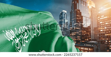 Saudi Arabia national flag cloth fabric waving on beautiful buildings background.