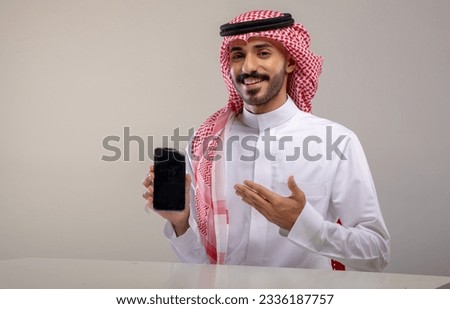 A Saudi character holding a phone sitting in the office on a white background