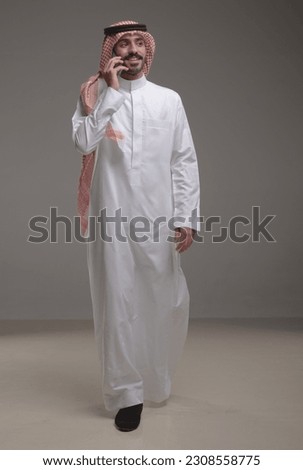 A Saudi character wearing thob using a phone on withe background