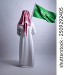 Saudi man holding the Flag of Saudi Arabia isolated on white background back view 