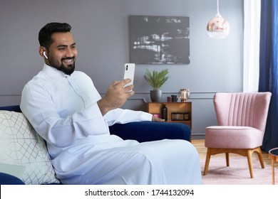 Saudi man video calling at home sitting at sofa in living room                    