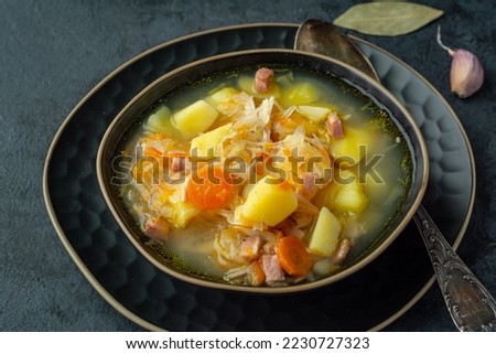 Sauerkraut soup with potatoes, carrots and bacon. Soup with cabbage