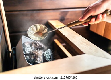 Sauna in Finnish spa. Hot steam, water on stones. Man in wellness and health room in Finland. Warm temperature bath therapy. Traditional summer cabin relaxation. - Shutterstock ID 2159654283