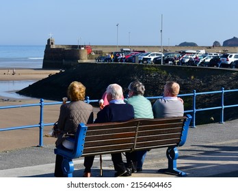 Saundersfoot, Pembrokeshire,Wales UK -3.23.2022: A Group Of Friends Enjoy An Ice-cream Overlooking The Beach And Harbour Entrance At Low Tide.