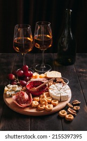 Sausage and cheese cut with fruit, cookies and sauce with two glasses of white port and a bottle. Wine appetizer, Charcuterie and cheese platter