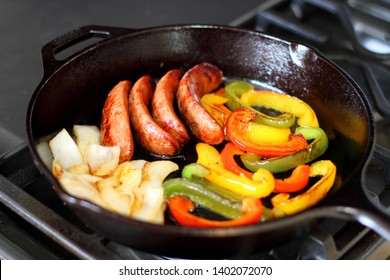 Sausage cooking on the stove in a cast iron skillet with bell peppers and onion. - Shutterstock ID 1402072070