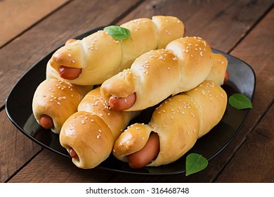 Sausage in the dough sprinkled with sesame seeds on a wooden background in rustic style - Shutterstock ID 316468748