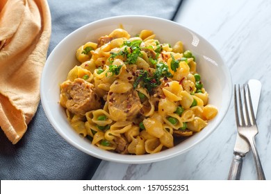 Sausage Macaroni And Cheese With Green Peas In Bowl On Marble Kitchen Table