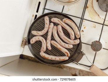 Sausage Meat Cooking On A Frying Pan In A Messy Kitchen. Shot From Above.
