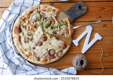 Sausage, mushroom, bell pepper, and mozzarella pizza placed on a round cutting board - photographed from above (flat lay). - Powered by Shutterstock