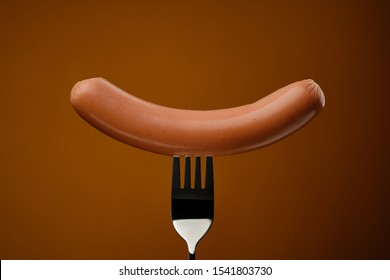 Sausage On A Fork Isolated. Brown Background