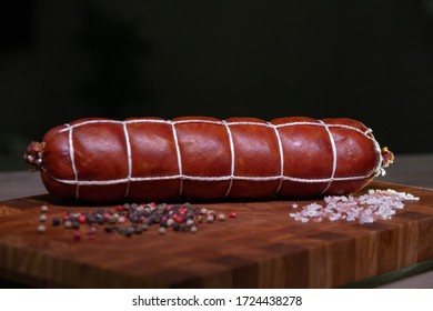 Sausage With A Plait On A Wooden Board With Pepper And Salt