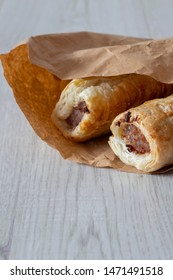 Sausage Rolls In A Brown Paper Bag, Environmentally Friendly Biodegradable Packaging, With A Grey Wood Background