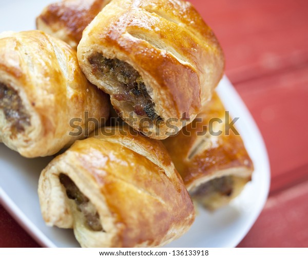Sausage rolls on a\
plate on a wooden table