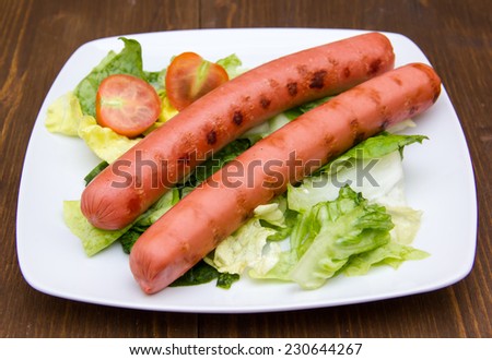 Sausages with salad on plate on wooden table