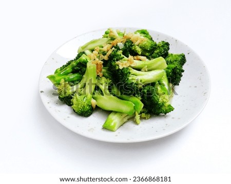 Sauteed Garlic Broccoli or Tumis Brokoli Bawang Putih in Indonesian is a stir fried broccoli with garlic on top. Chinese Food. Served on a white plate and isolated on a white background.