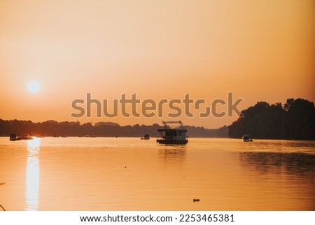 The Sava river between Bosnia and Croatia with boats floating in it under a bright golden sunset sky Stok fotoğraf © 