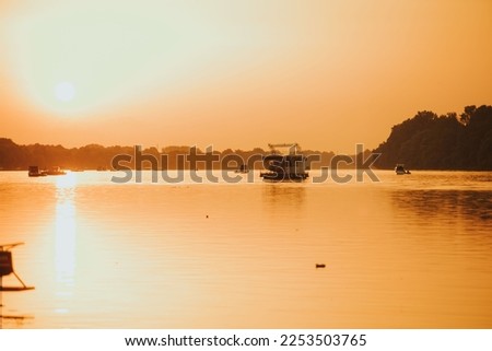 The Sava river between Bosnia and Croatia with boats floating on it under a bright golden sunset sky Stok fotoğraf © 