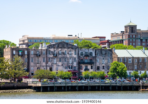 Savannah, USA - May 11, 2018:\
Cityscape skyline by River street old town waterfront with people\
walking in shopping district of restaurants, cafes and stores\
shops