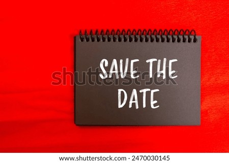 Save the date message written on black notebook page with red background. Conceptual save the date symbol. Copy space.