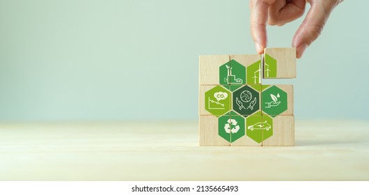 Save of earth, saving environment, net zero emissions concept. Green business and sustainable development. World earth day. Hand puts wooden cubes with clean energy icon standing on eco friendly icon. - Shutterstock ID 2135665493