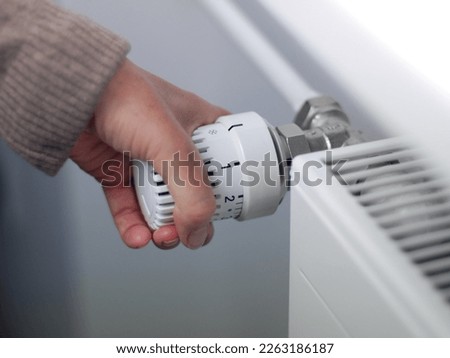 Save energy: one hand operates the temperature controller radiator, close up 